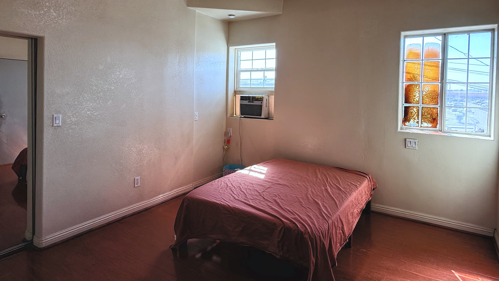 Upstairs bedroom with two windows, textured walls, white base trim and a mirrored sliding closet door.