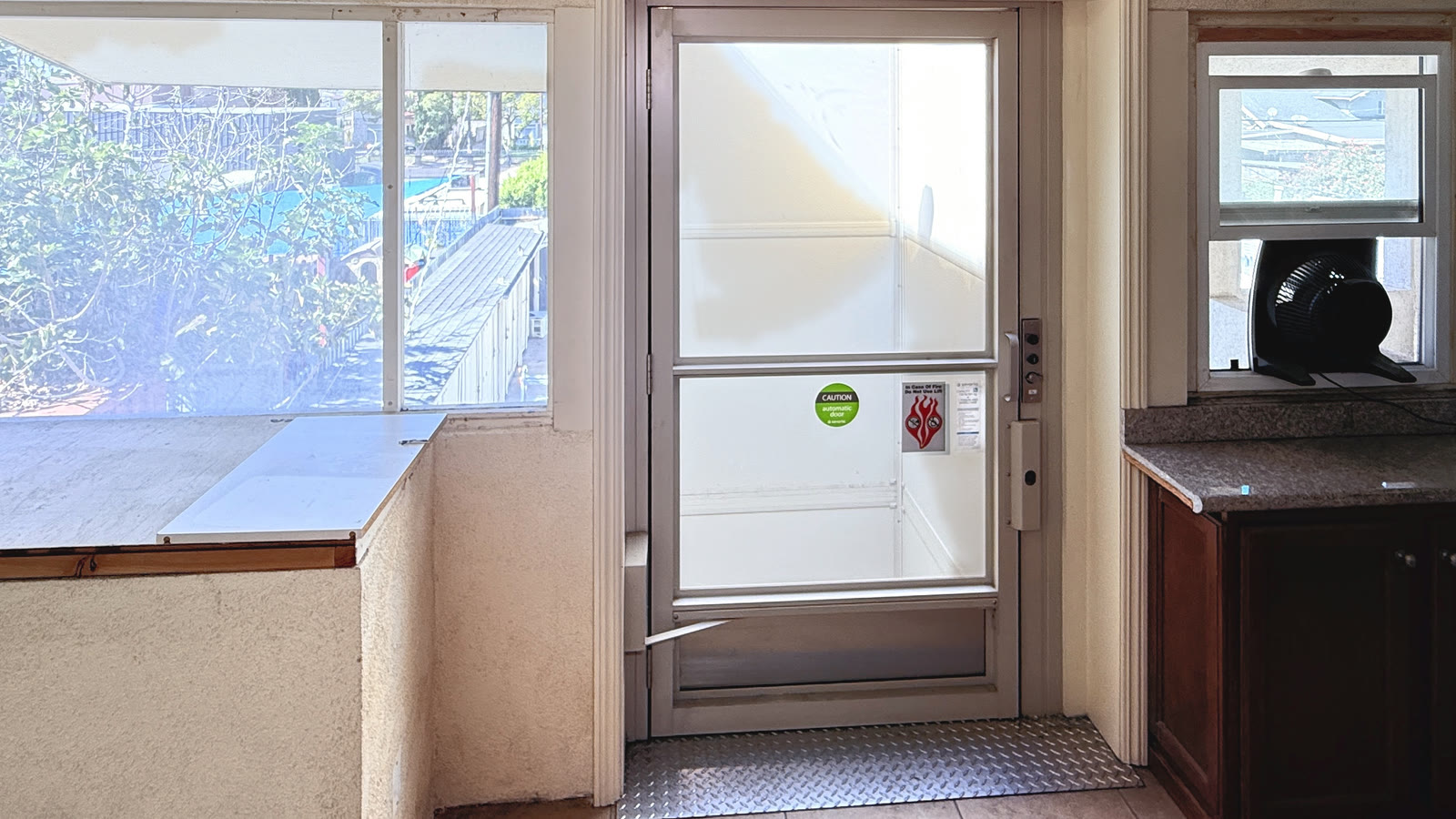 The wheelchair lift's glass-paneled door at the upper landing, with the white lift cab visible through the glass.